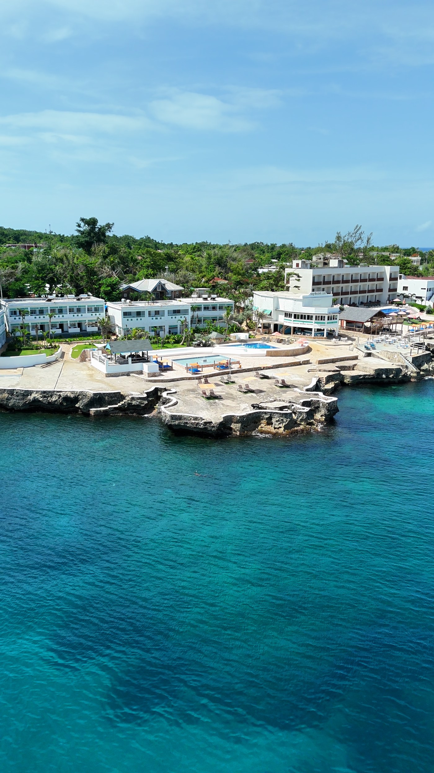 Cliffside guesthouses and pools on the Negril West End, seen from the air