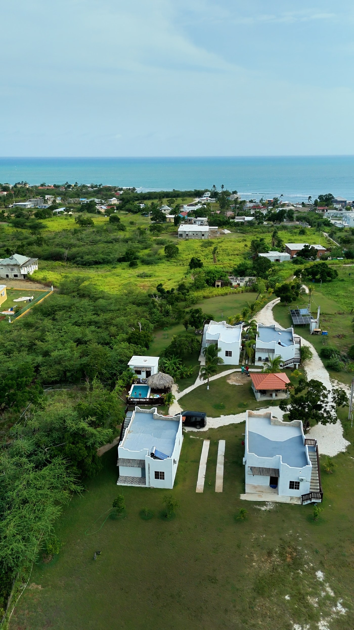 White cottages and a pool set back from the sea at Treasure Beach